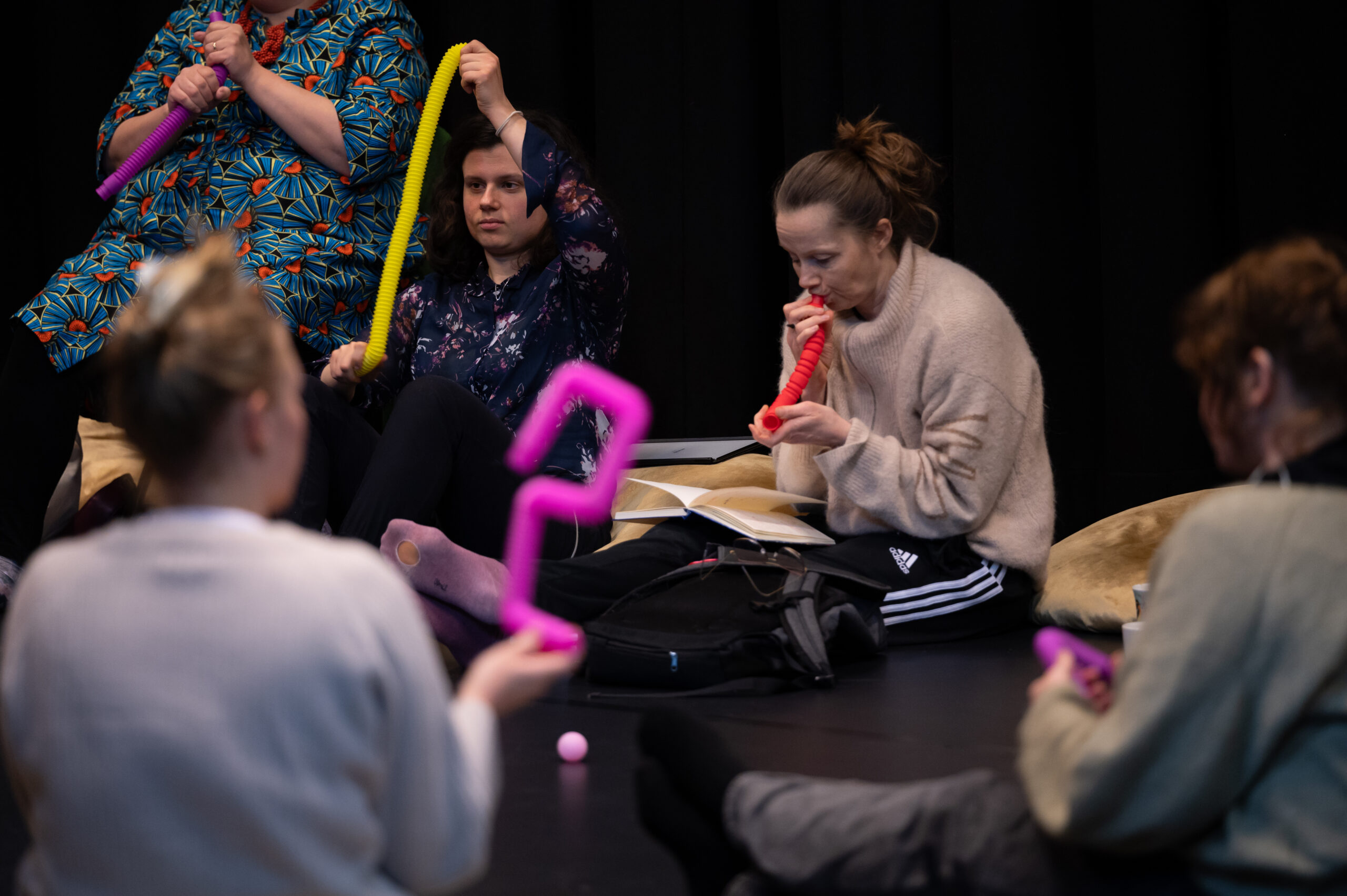 A group of people sitting together playing with bendy tube toys of different colours
